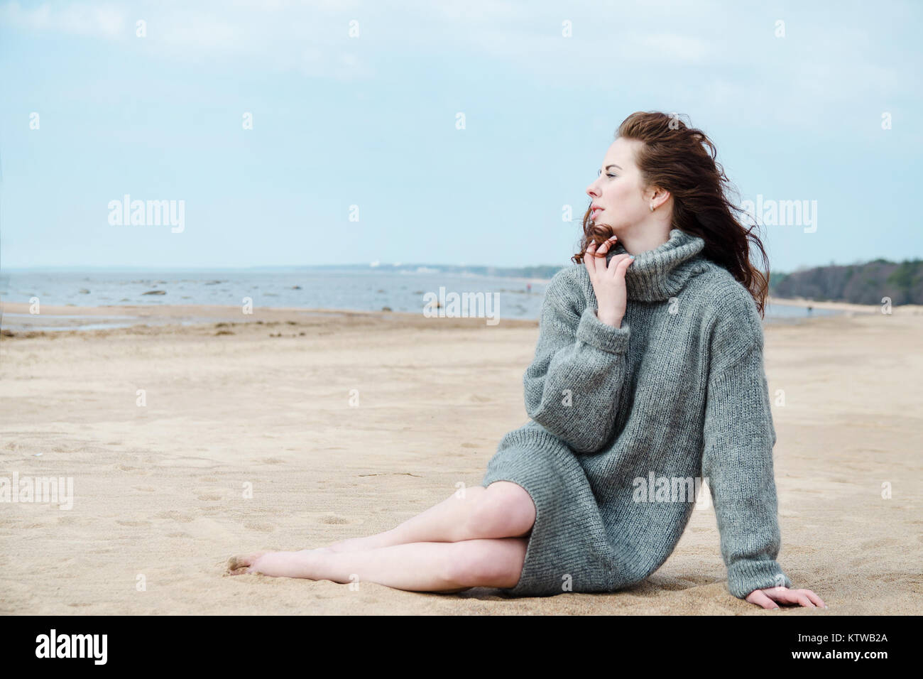Attractive woman wearing a warm cardigan at the cold beach. Stock image. Stock Photo