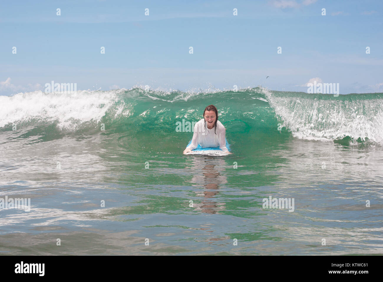 Girl on the waves in the ocean with her Surfboard. Stock image Stock Photo