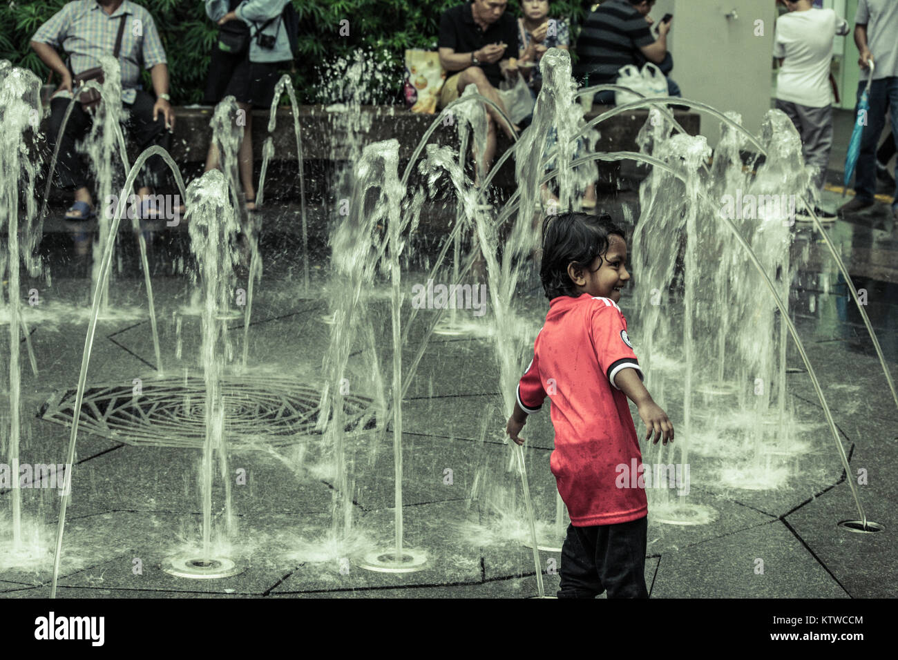 Asian kid playing with water fountain Stock Photo - Alamy