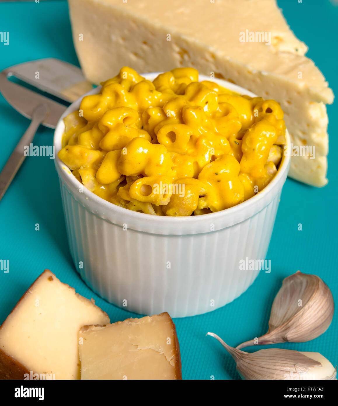 Bowl of yellow cheddar macaroni mac and cheese on blue table surrounded