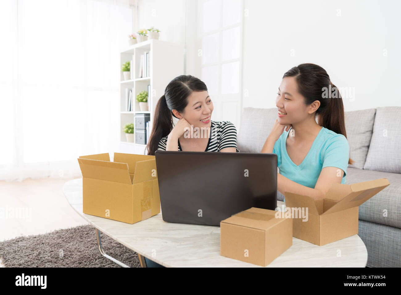 cheerful young sisters discussing to buy present for parents during special festival holiday through online shopping system. Stock Photo