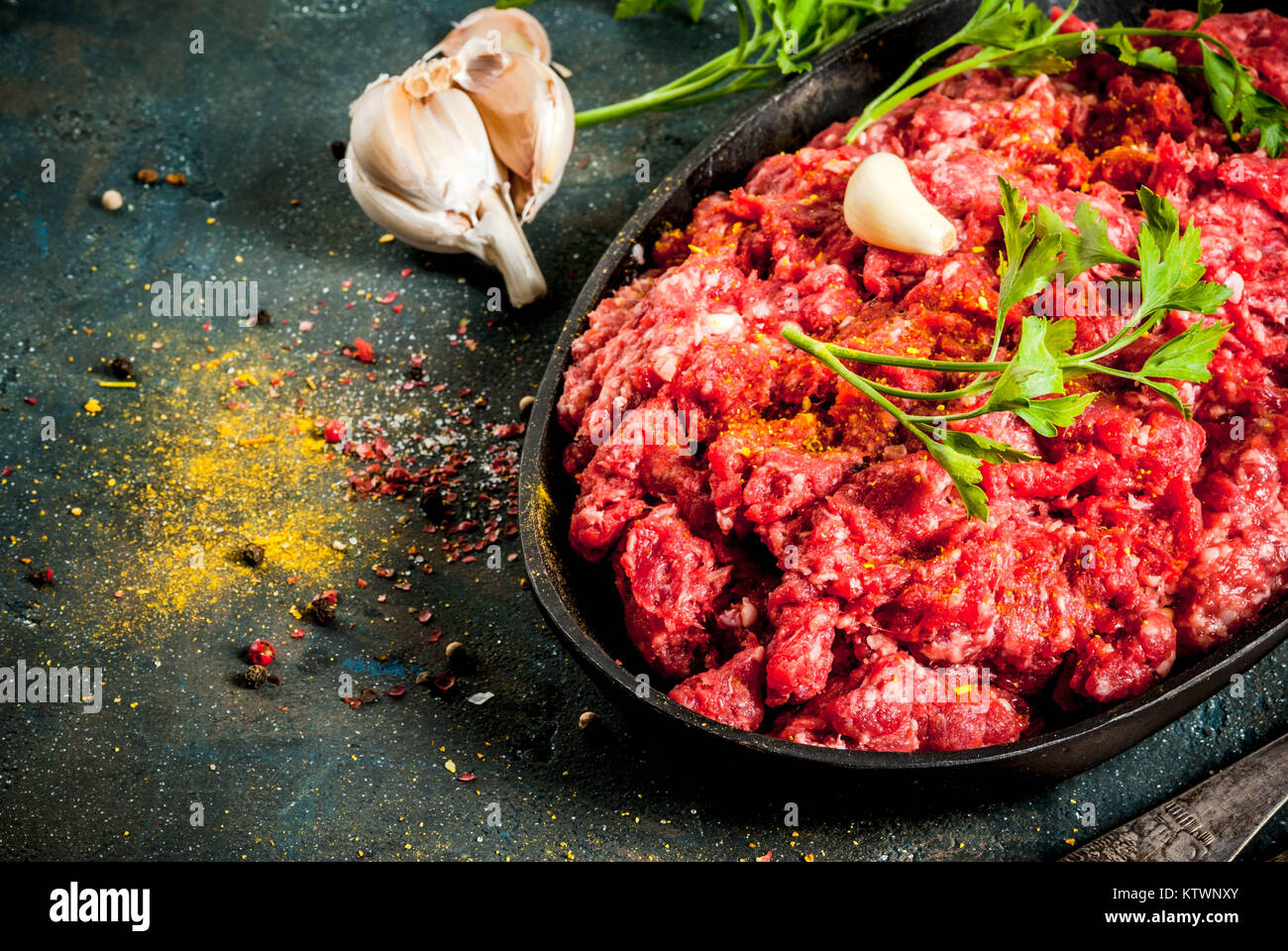 Minced meat with spices and fresh herb on dark table, copy space Stock