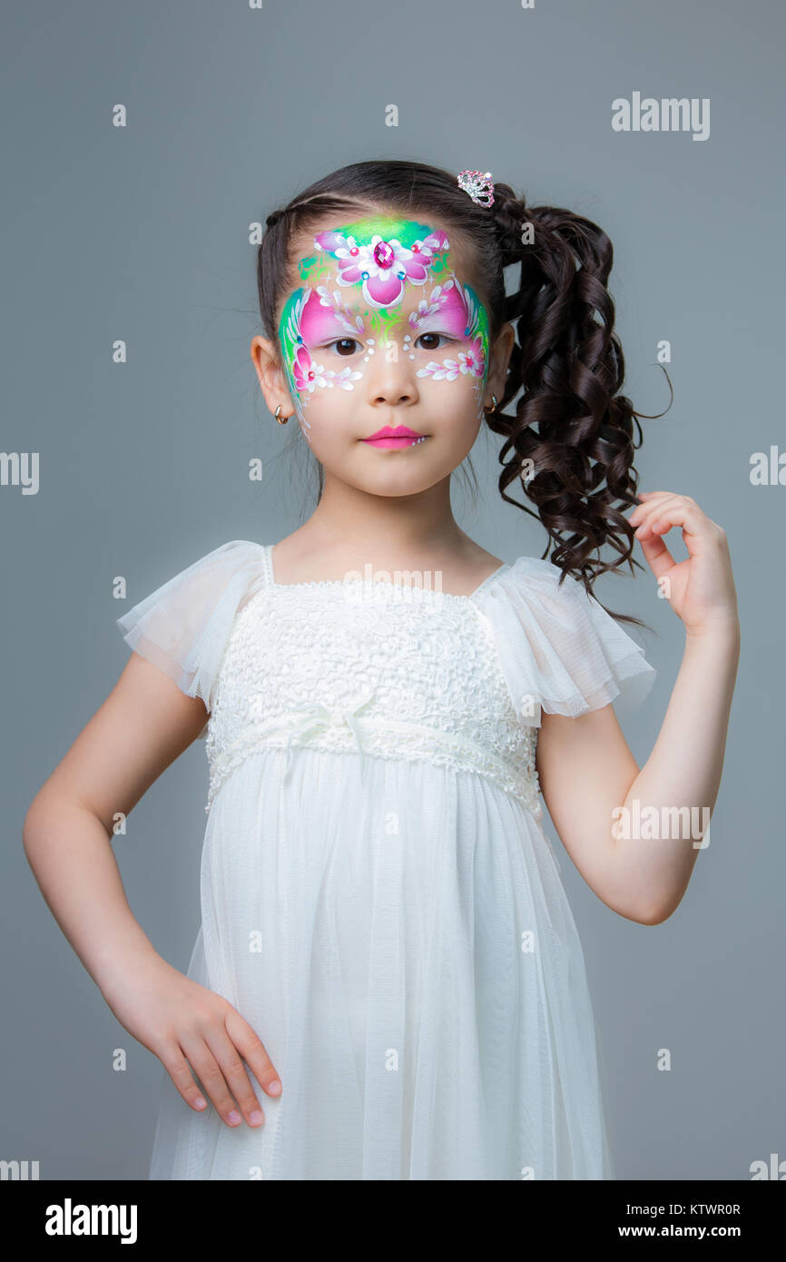 A small beautiful Kazakh girl with painted flowers on her face. Face painting Stock Photo