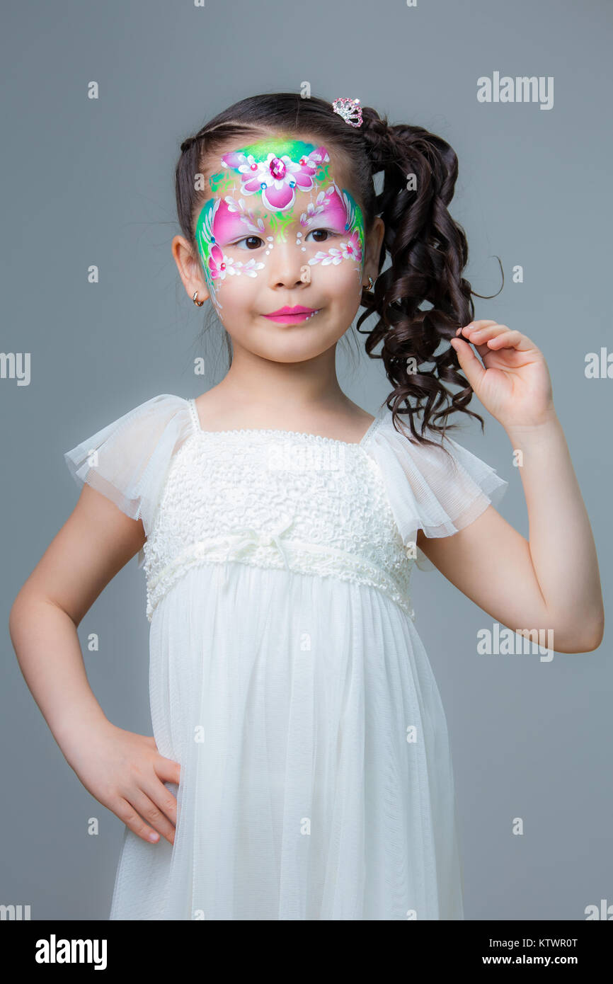 A small beautiful Kazakh girl with painted flowers on her face. Face painting Stock Photo