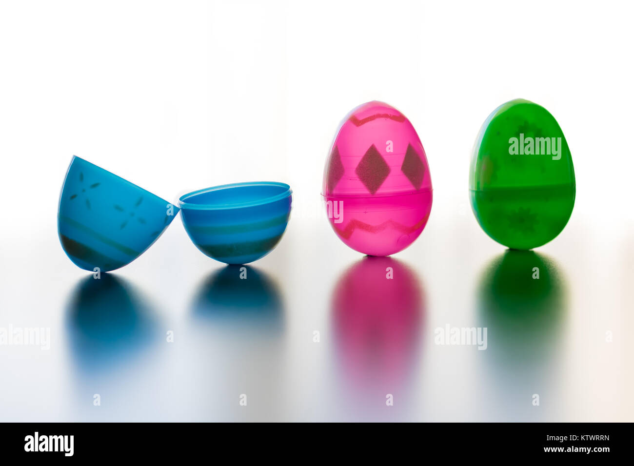 Blue, pink and green designed easter eggs are photographed stand up. The blue egg is opened symbalizing Jesus' openned tomb. The eggs cast colored sha Stock Photo
