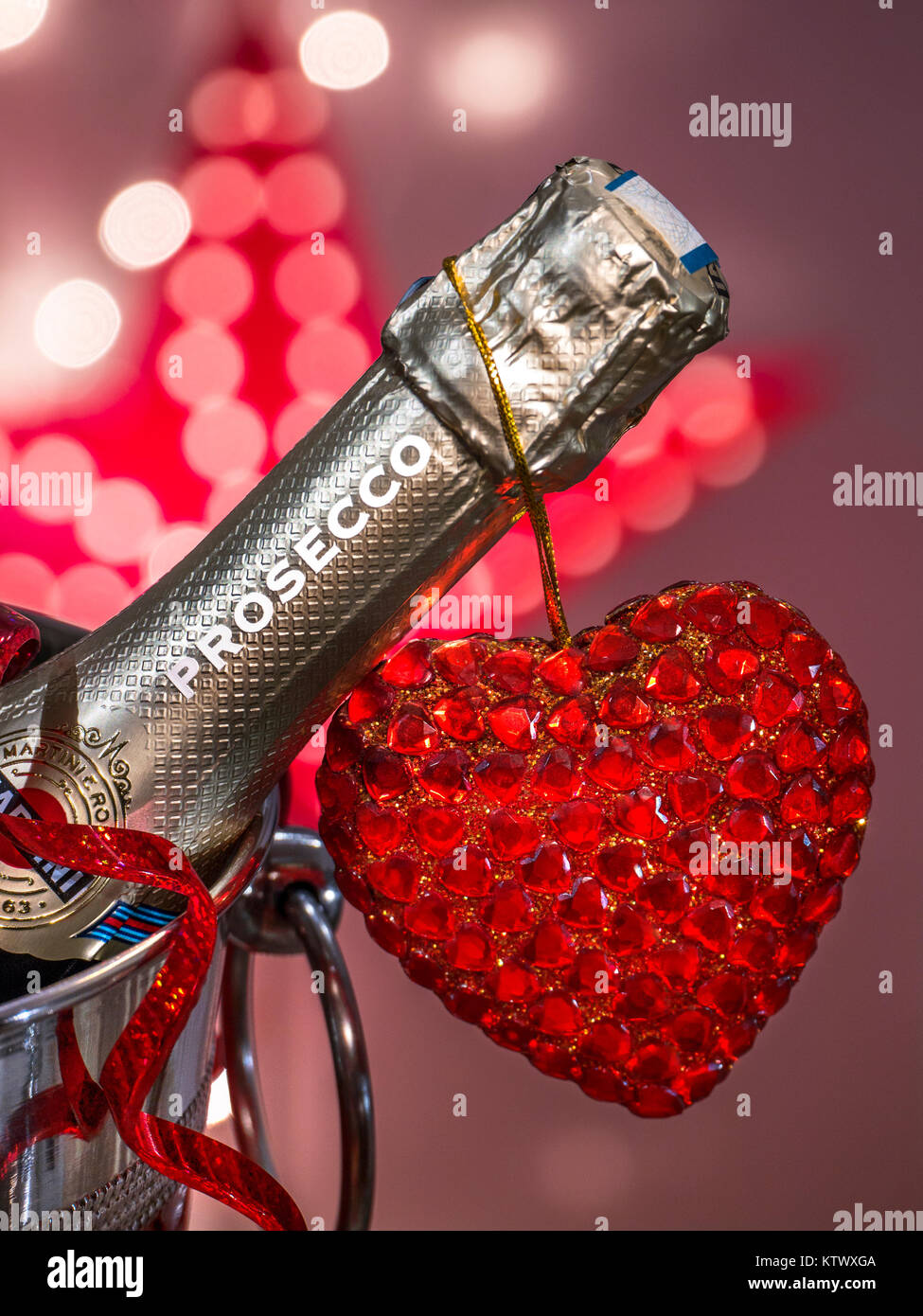 PROSECCO LOVE ROMANCE PARTY LIGHTS Prosecco bottle on ice in wine cooler with  party streamer & sparkling love heart and celebration lights Stock Photo