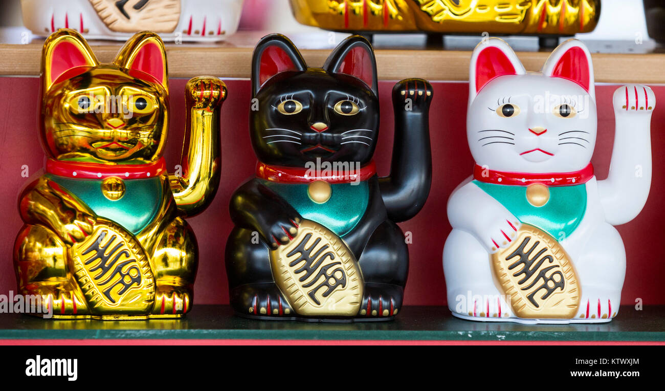 Three Chinese lucky cats, also welcoming cats, beckoning cats, fortune cats or money cats, Maneki-neko or Manekineko , at a market stall, shop, bringing good fortune for the Chinese New Year Stock Photo