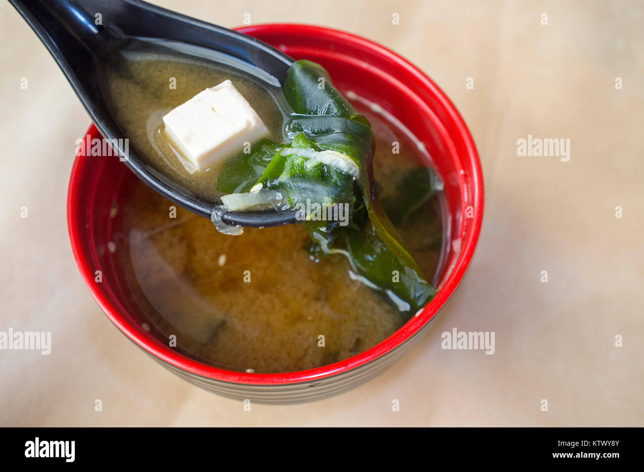 Japanese miso soup with tofu and seaweed. Clay spoonful closeup with one tofu piece Stock Photo