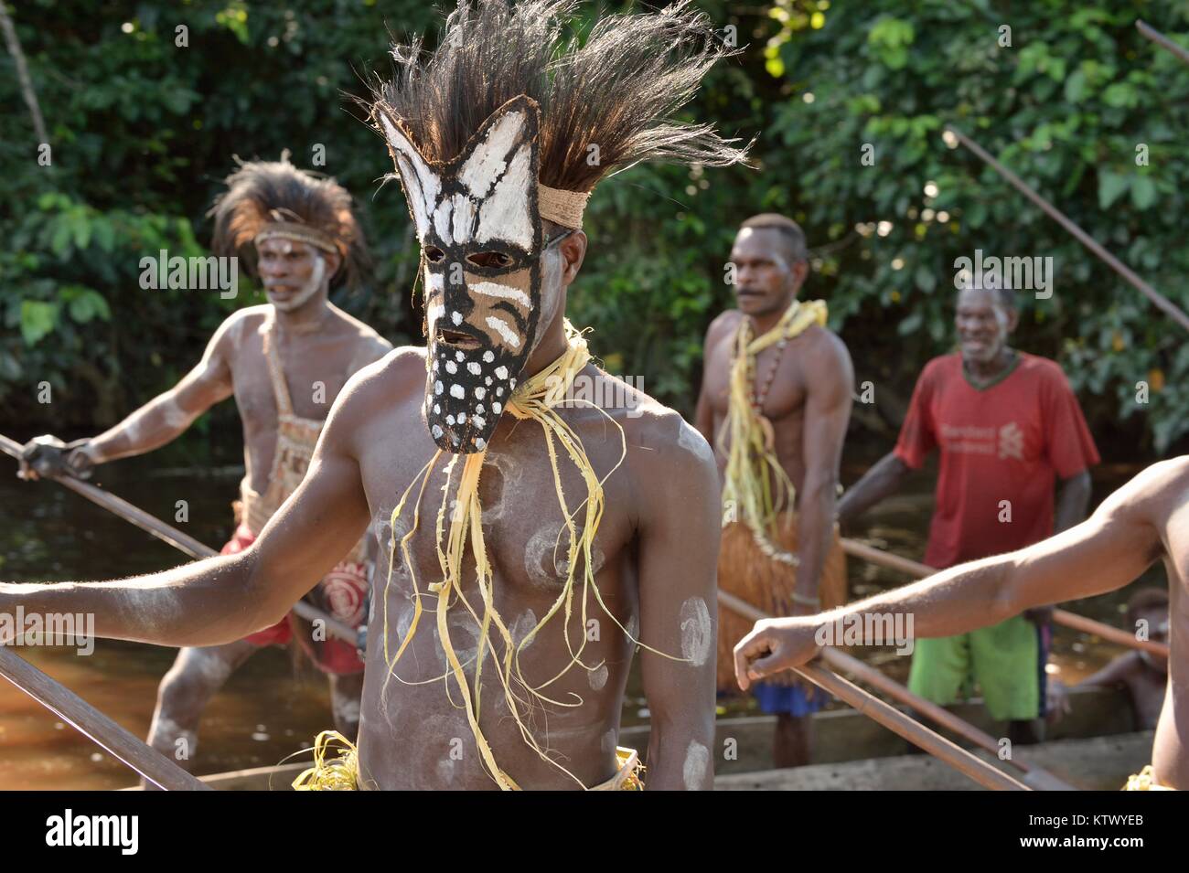 Head hunter of a tribe of Asmat in mask. Traditional facepainting and headdress. Stock Photo