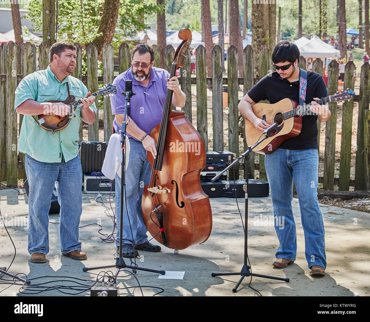 American bluegrass band, trio, on stage performing with guitar, bass and mandolin at a local crafts fair in rural Alabama. Stock Photo