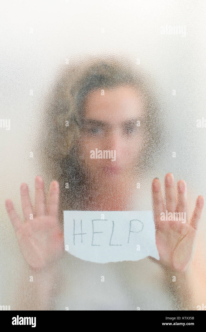 Abused woman seeks help from violence holding a paper with text help writen on it Stock Photo