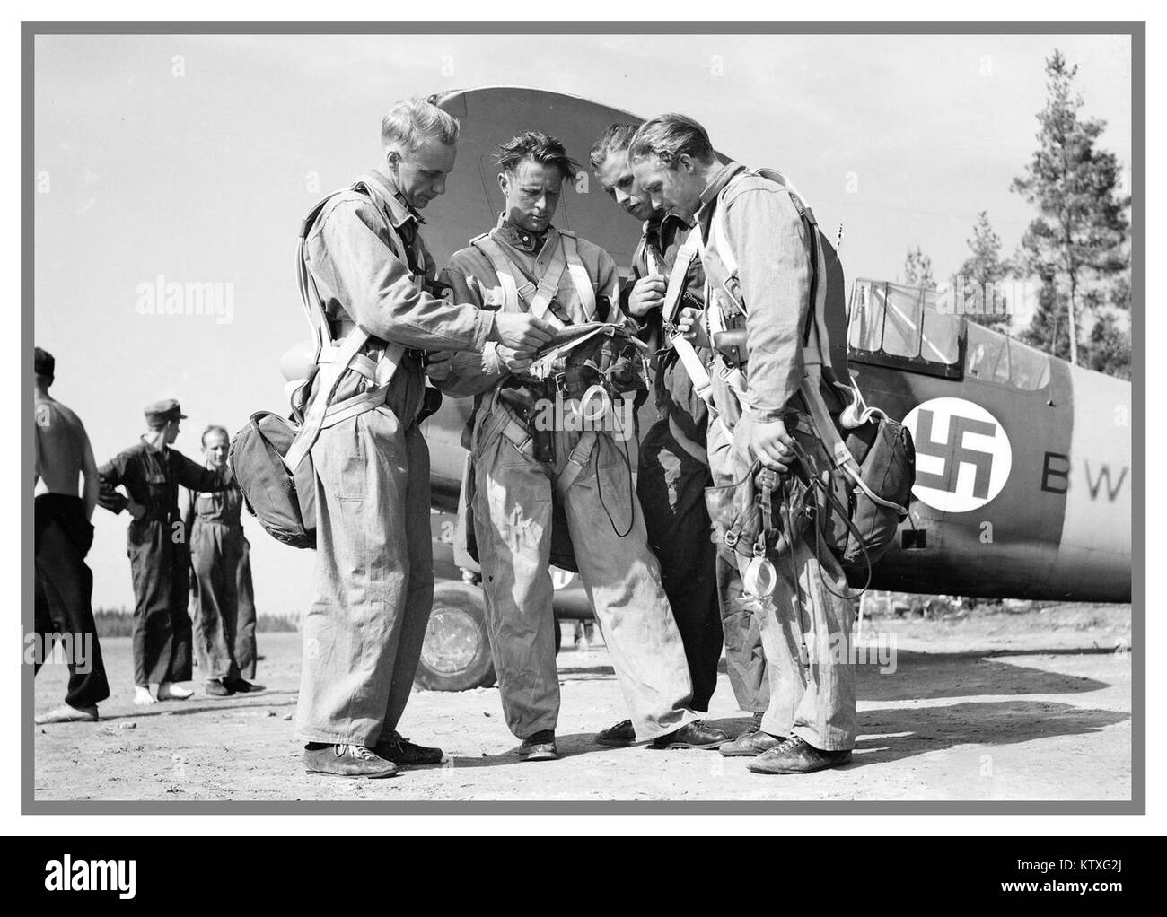 Finnish Airforce pilots during Winter War with American Brewster F2A Fighter planes behind with Swastika emblem on fuselage. Stock Photo