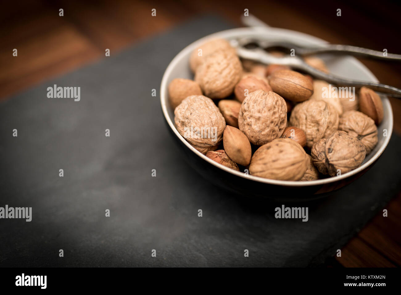 A bowl of mixed whole nuts in their shells including walnuts, hazelnuts