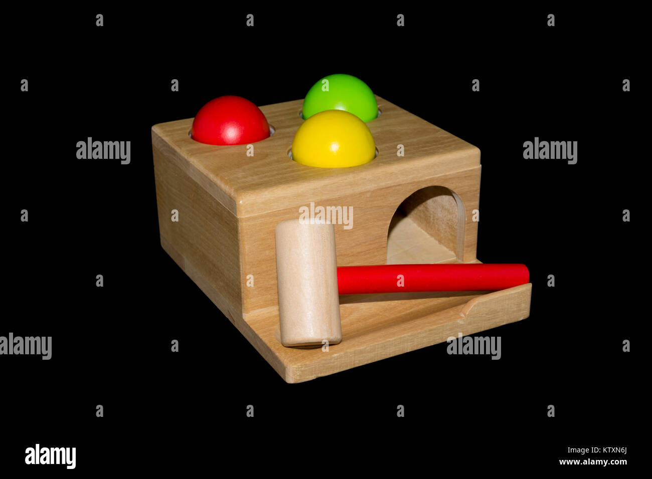 A wooden hammering toy with three coloured balls and a hammer isolated against a black background Stock Photo