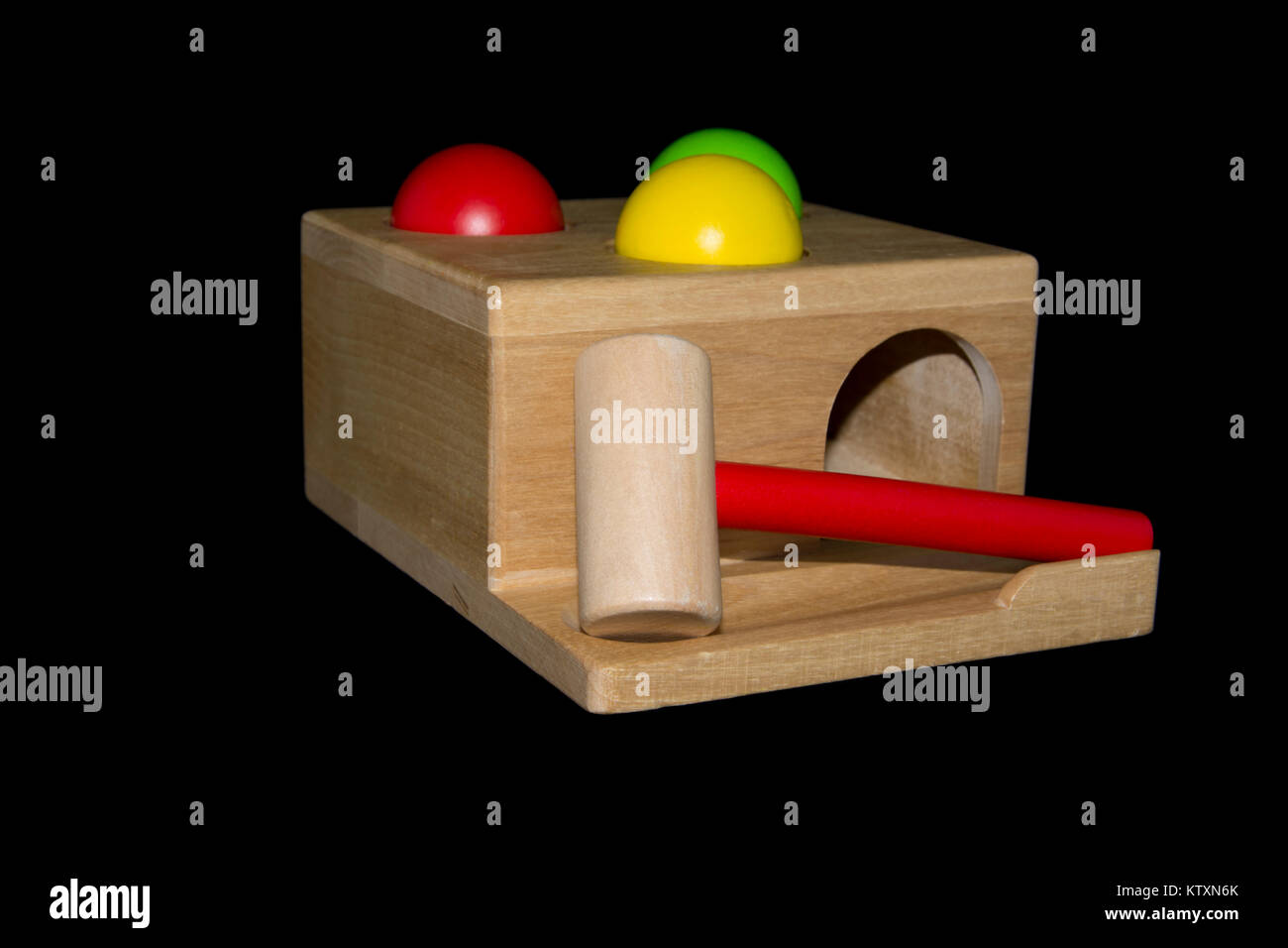 A wooden hammering toy with three coloured balls and a hammer isolated against a black background Stock Photo