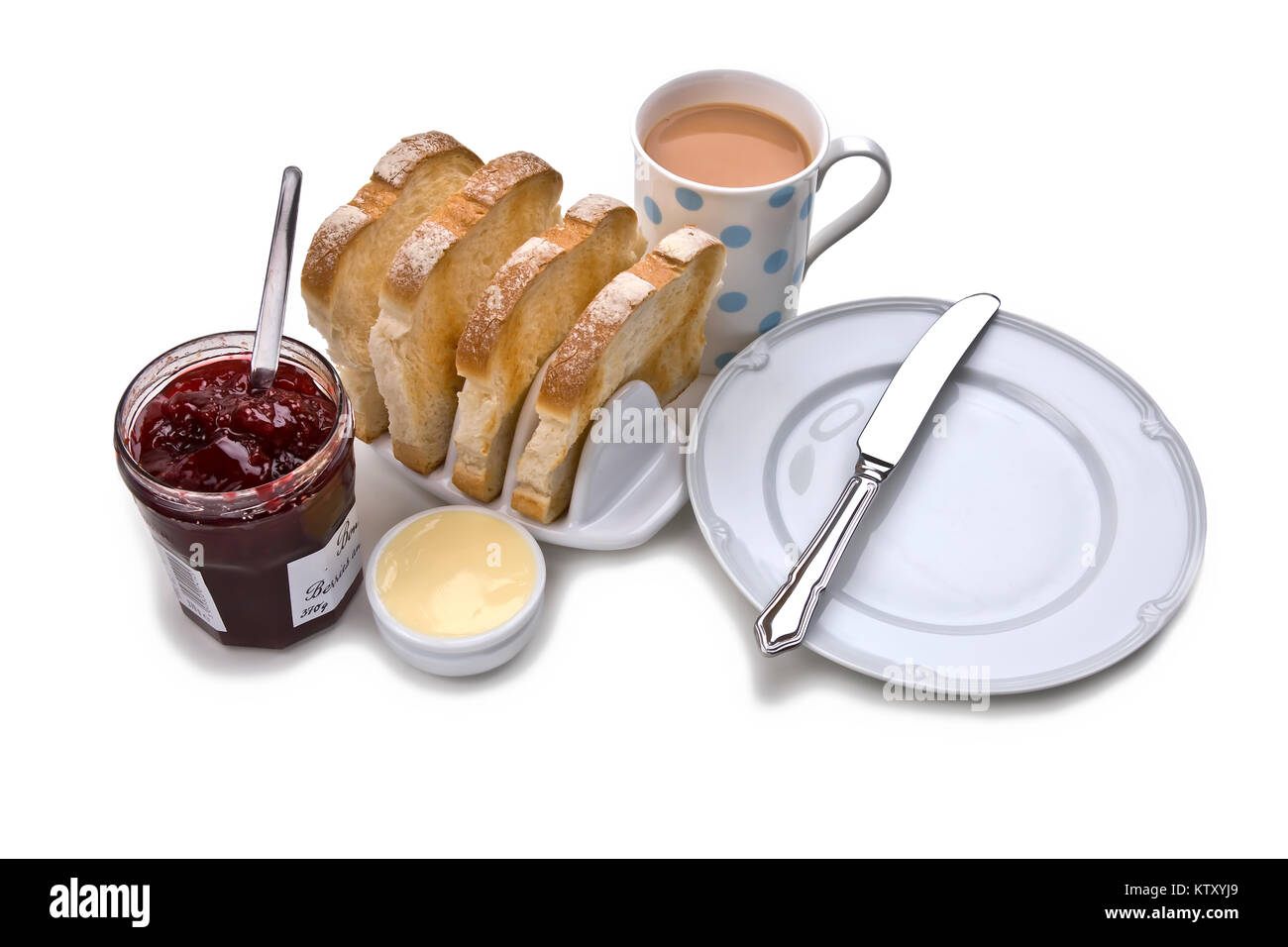 White toast breakfast with ceramic toast rack, butter; red jam, mug of tea, serving plate and knife on white background Stock Photo