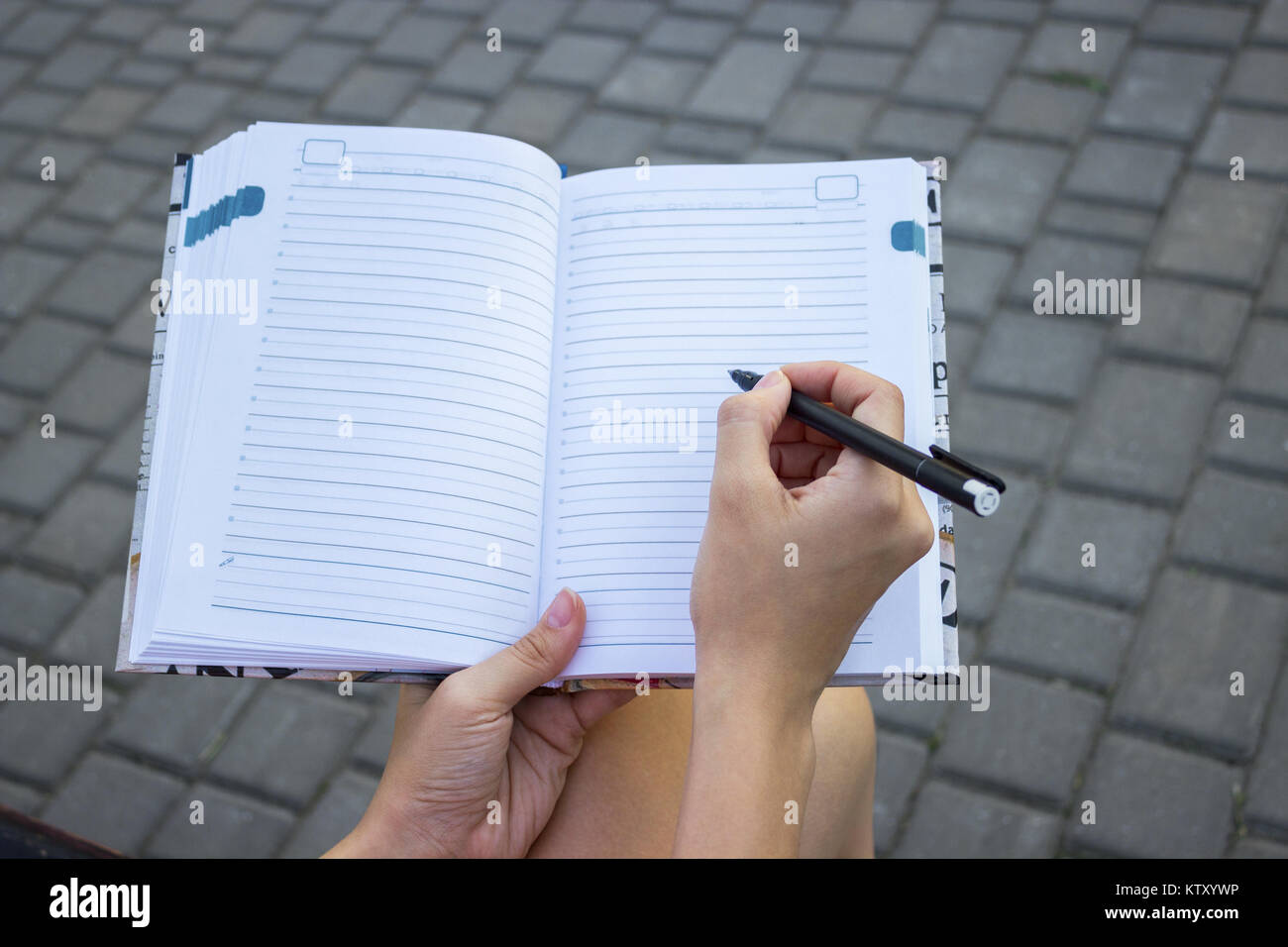 Tender girl's pale hand holding a pen and writing on the blank pages of ...