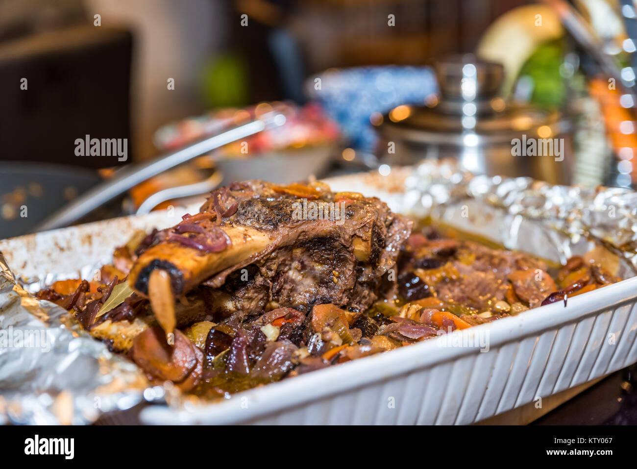 Roasted beef rib steak with bone in roasting tray on busy kitchen table
