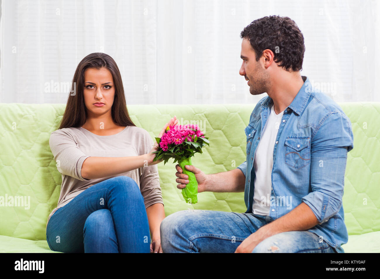 Young couple is sitting at sofa at home. Woman is angry Stock Photo - Alamy