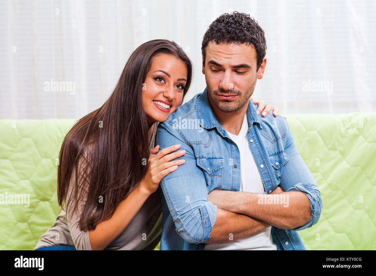 Young couple is sitting on sofa at home. Man is angry Stock Photo - Alamy