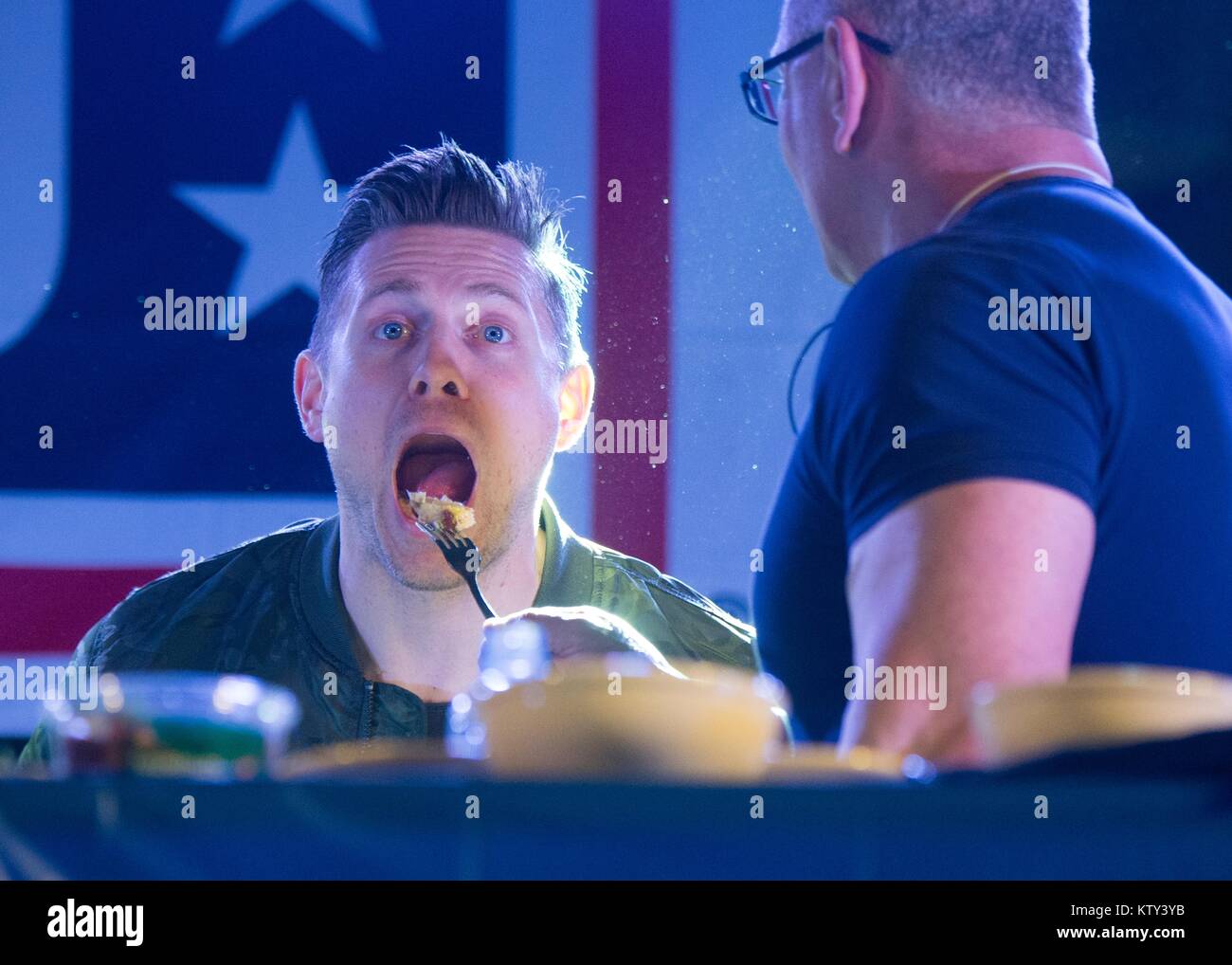 Professional chef Robert Irvine feeds World Wrestling Entertainment (WWE) wrestler The Miz (Michael Mizanin) during a cooking demonstration for U.S. soldiers for the USO Holiday Tour at the Moron Air Base December 21, 2017 in Sevilla, Spain. Stock Photo