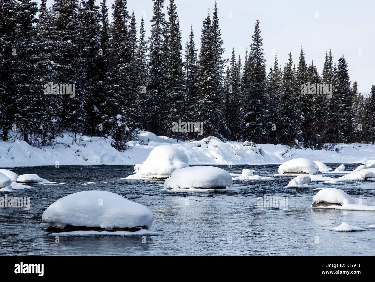 Water flows around snowy rocks at the Gulkana Wild and Scenic River March 18, 2016 in Alaska. Stock Photo