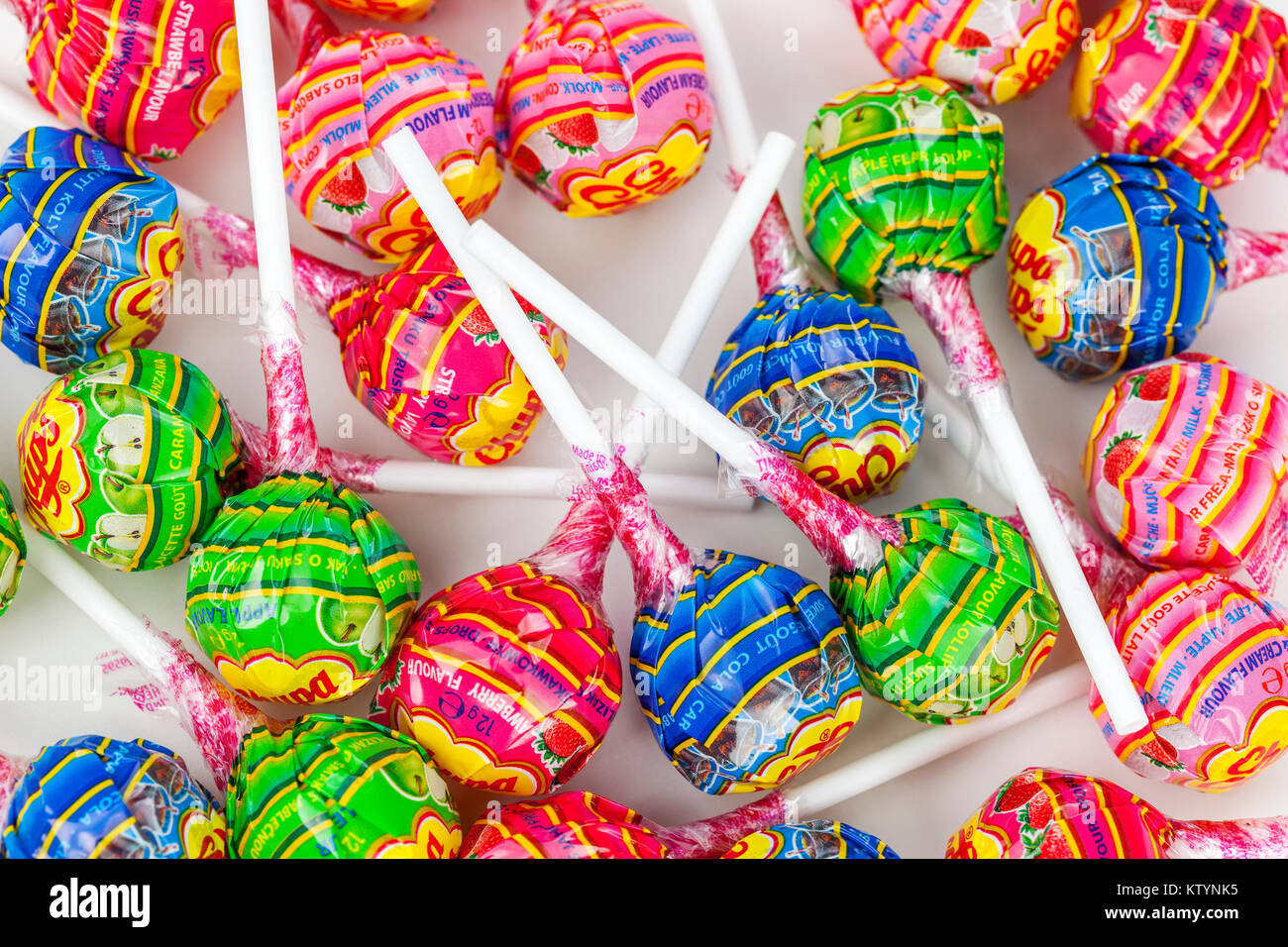 Variety of multi coloured lolly pops with white sticks in wrappers laying on a sweet counter Stock Photo