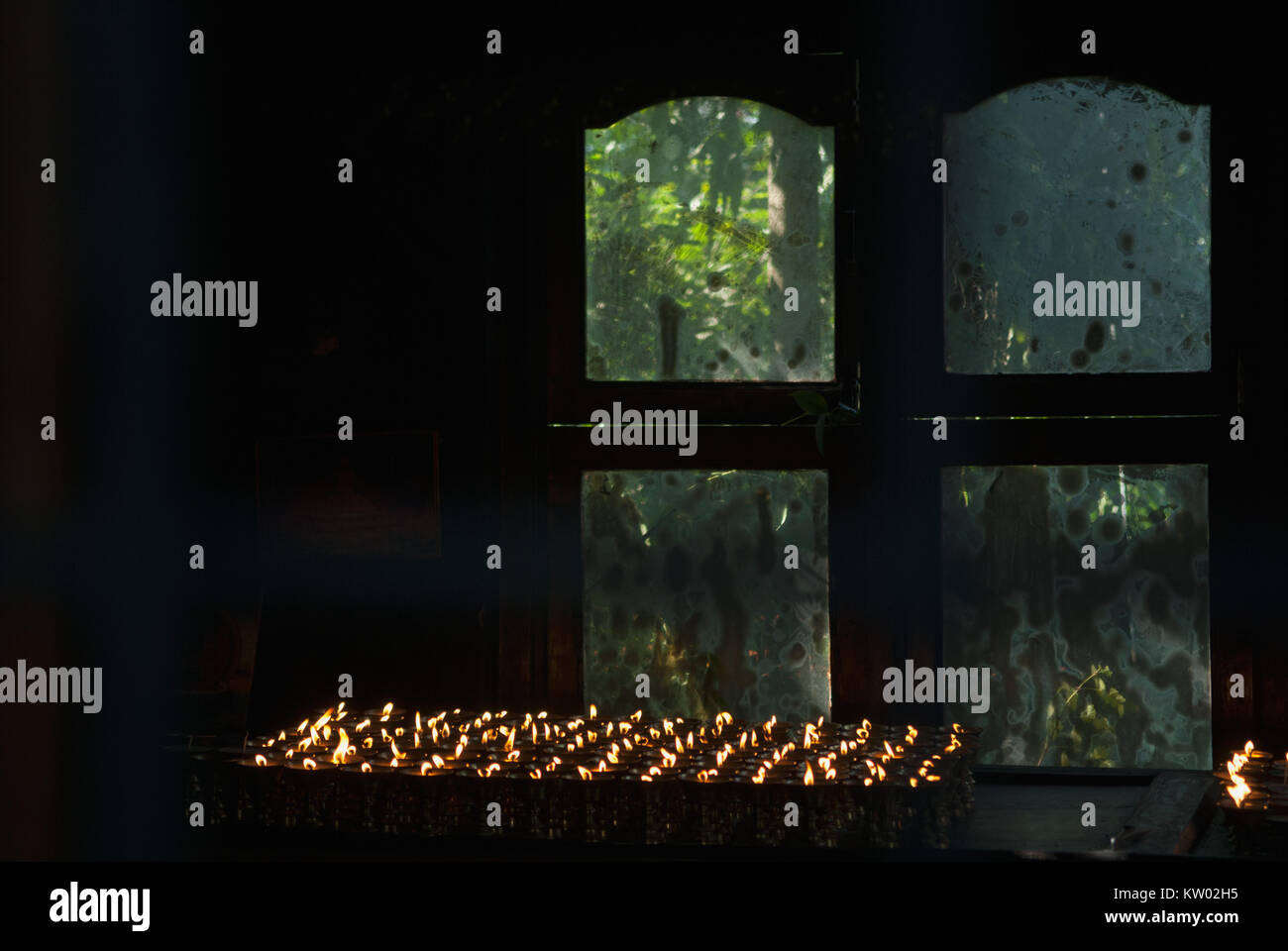 Buddhist Oil Lamps In A Dark Room In Front Of The Window