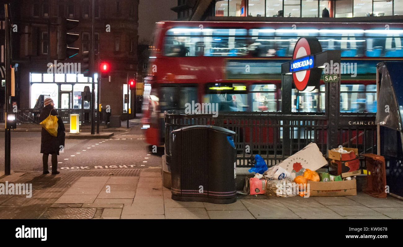 London, England, UK - December 31, 2010: A pedestrian waits to cross the street as a traditional red double-decker London bus passes at Chancery Lane  Stock Photo