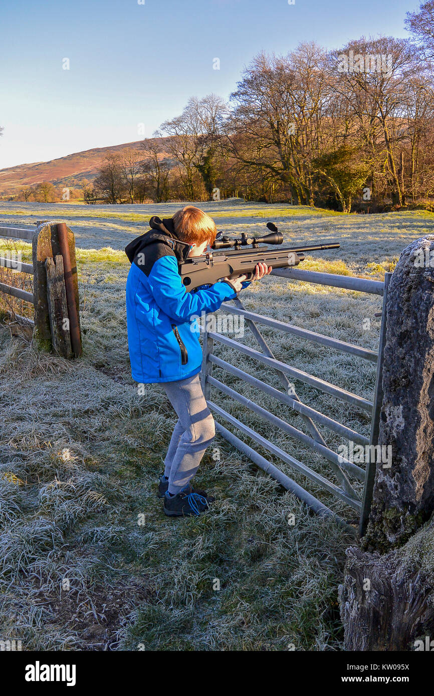 Teenage boy firing an air rifle on farmland on a cold, frosty day. Stock Photo