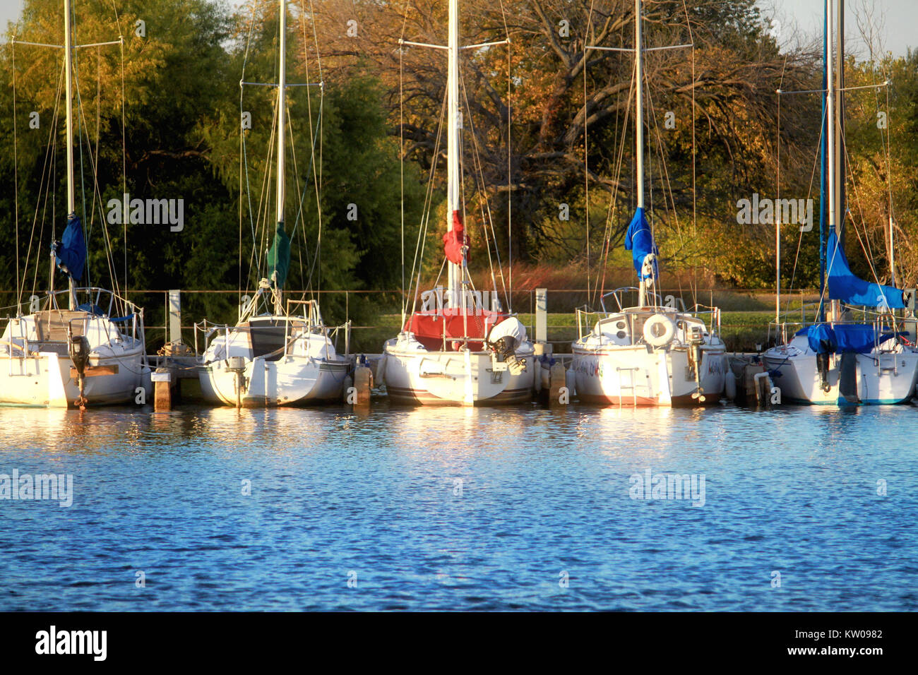 Five sailboats sit at rest in the docks of Lake Hefner in Oklahoma City at the beginning of sunset. Stock Photo