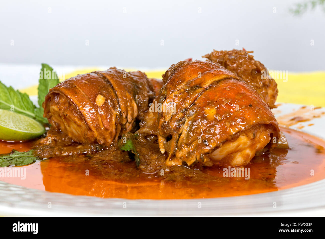 Lobster in tomato sauce served in a white dish and a slide of lemon