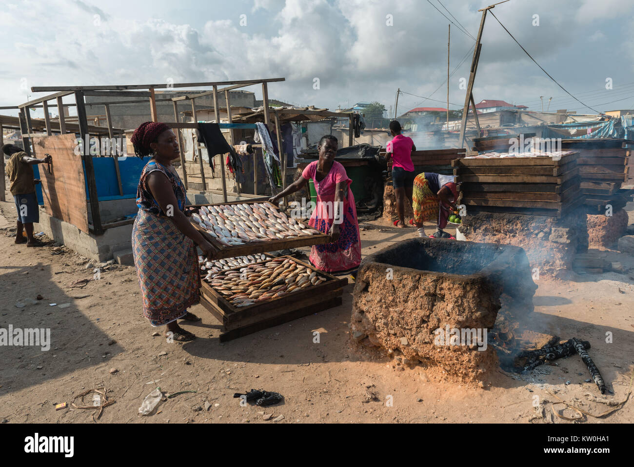 Two women smoking fish over a clay oven, Jamestown Fishing Village