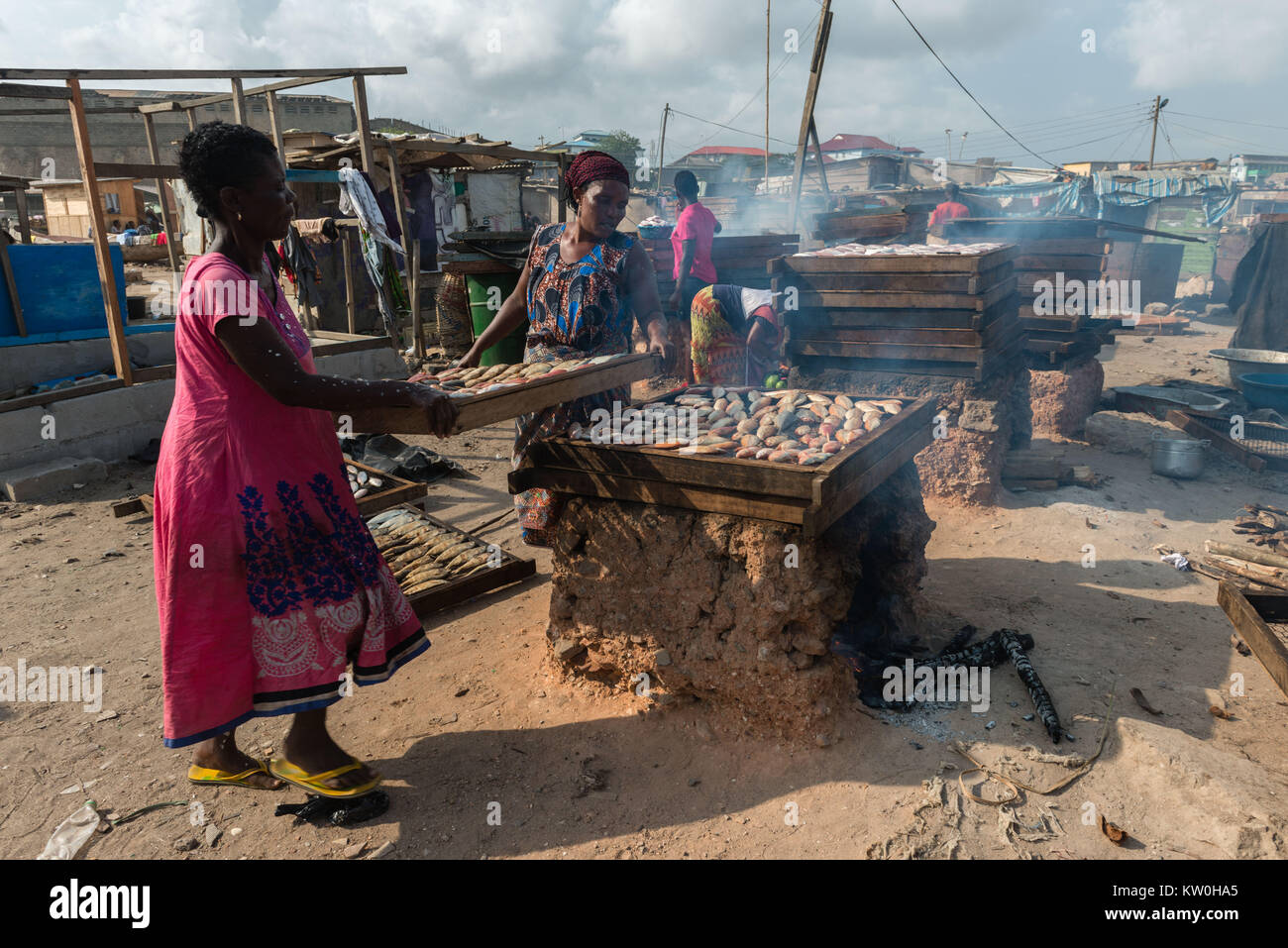 Two women smoking fish over a clay oven, Jamestown Fishing Village