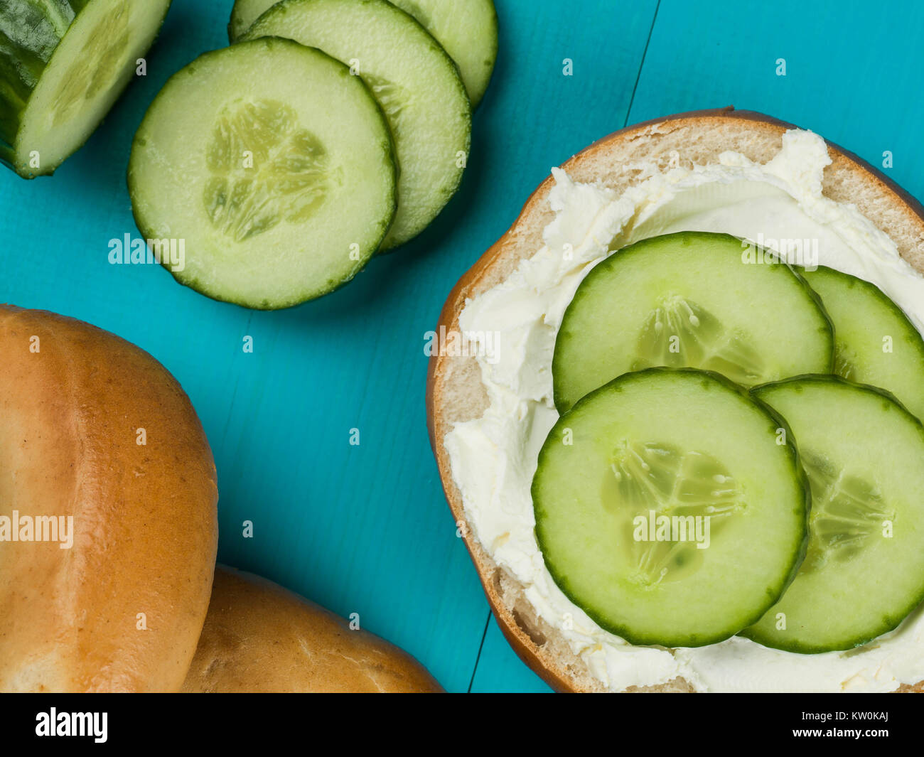 Cucumber and Cream Cheese Bagel Against a Blue Background Stock Photo