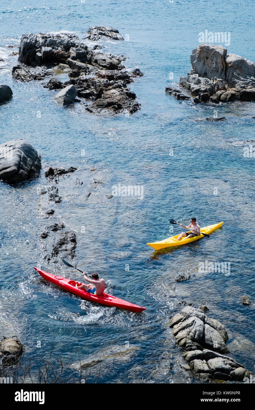 Two kayakers manouver in shallow water amongst the rocks of the Costa Brava, Spain, near the town of Calella de Palafrugell Stock Photo