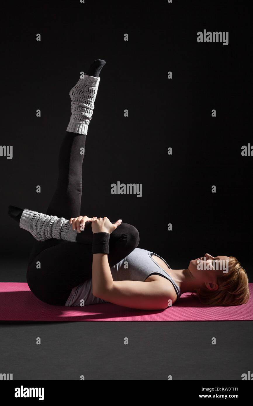 Young woman practicing yoga, Pawanmuktasana / Wind Relieving pose Stock