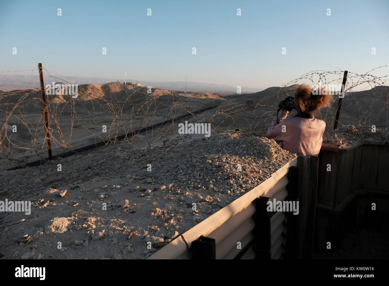 A young Israeli woman taking photos from an Israeli military defense position on a strategic hill near the cooperative agricultural community of Paran located in the western of the Arabah valley known in Hebrew as Arava or Aravah which forms part of the border between Israel and Jordan. Stock Photo