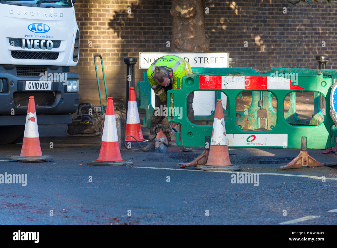 Construction worker using an angle grinder on the road, Ashford, Kent Stock Photo
