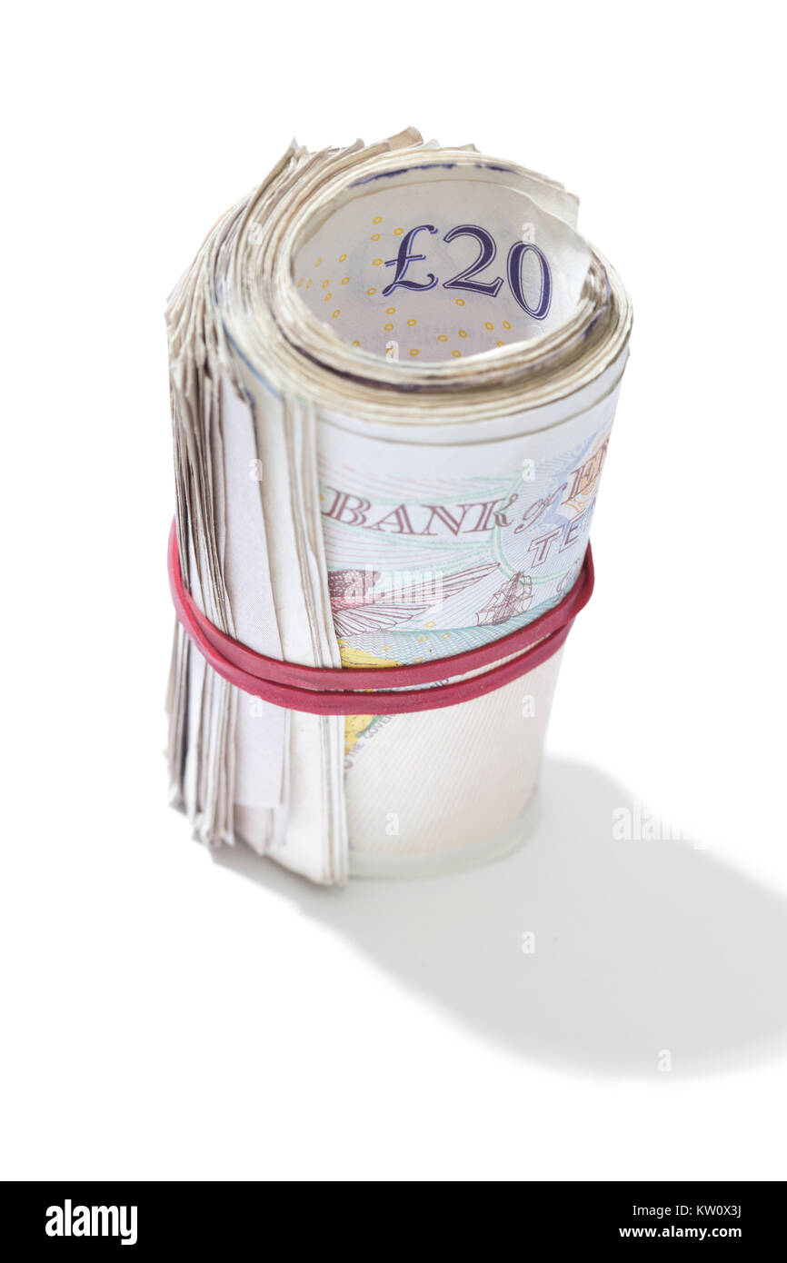 A roll of British notes held together by an elastic band on a white background. Stock Photo