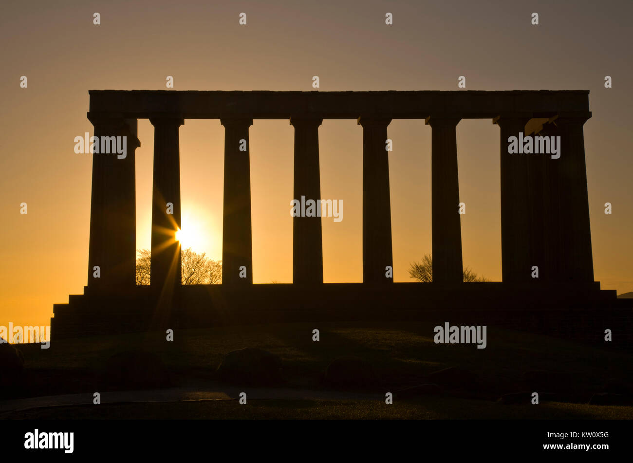 Rising sun flares through the columns of the National Monument in Edinburgh, Scotland Stock Photo