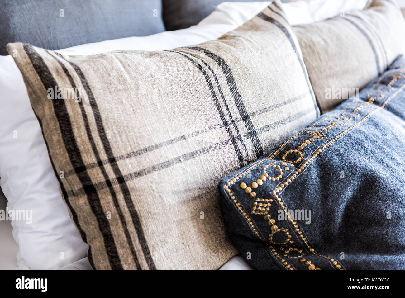 Closeup of new bed comforter with many decorative pillows in bedroom in staging model home, house or apartment Stock Photo