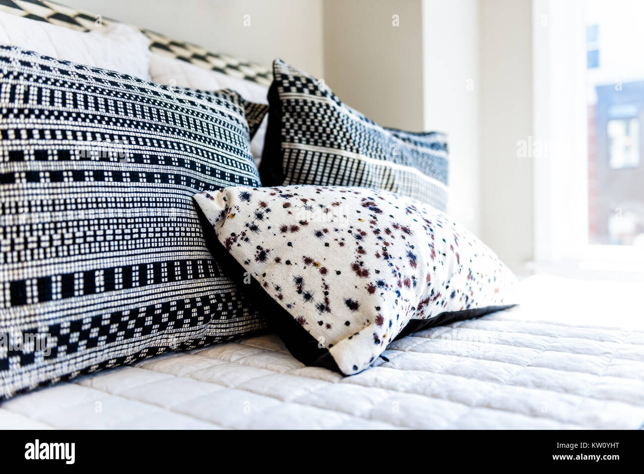 Closeup of new bed comforter with decorative pillows, headboard in bedroom in staging model home, house or apartment Stock Photo
