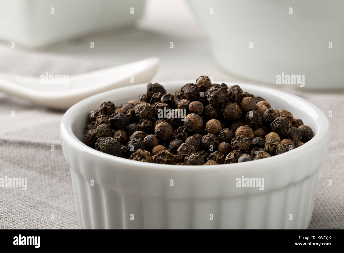 Raw, natural, unprocessed black pepper peppercorns white bowl on