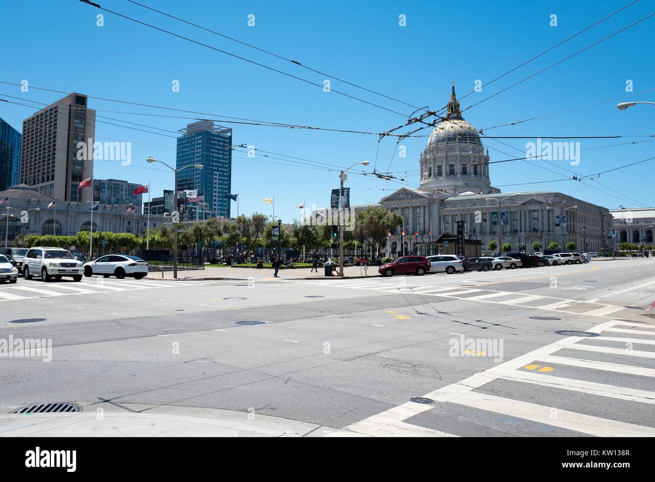 View of San Francisco's Civic Center neighborhood, including city hall, with overhead transit wires, vehicles and gay pride flags visible, San Francisco, California, June, 2016. Stock Photo