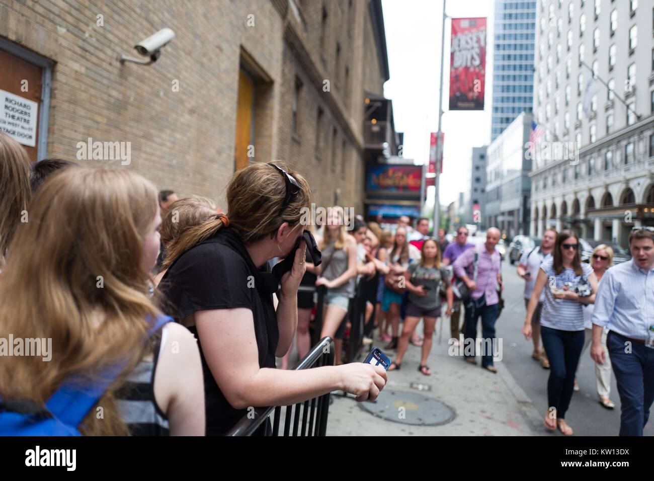 Before a performance of the Broadway musical Hamilton two days prior to creator Lin Manuel Miranda's departure from the show, fans relax while waiting at the stage door, New York City, New York, July 7, 2016. Stock Photo