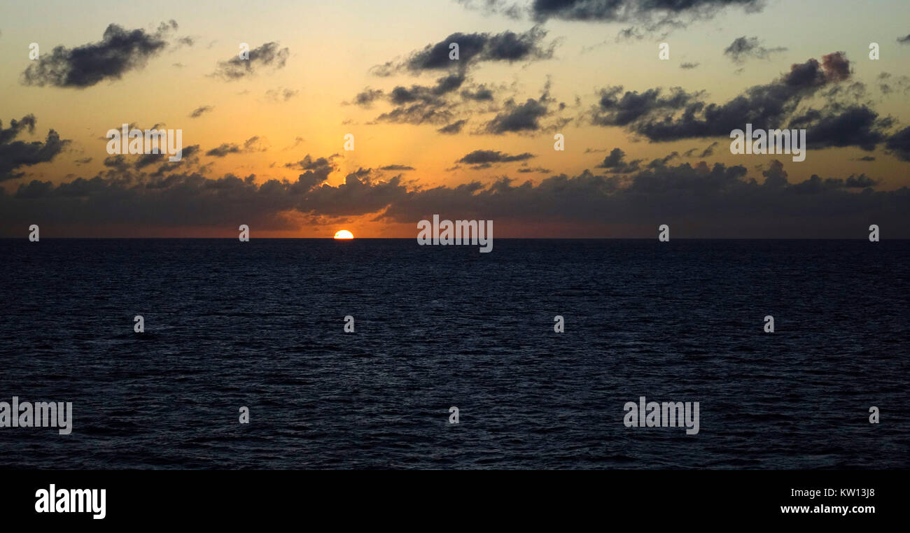 A setting sun disappears on the horizon in the Gulf of Mexico during a cruise. Stock Photo
