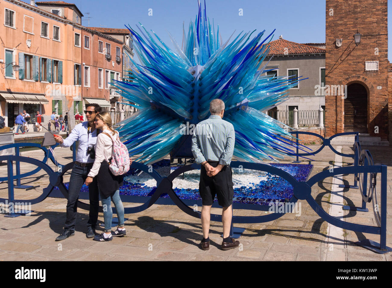 Tourists posing in front of the spectacular 'Comet Glass Star' sculpture on the island of Murano, Venice Stock Photo