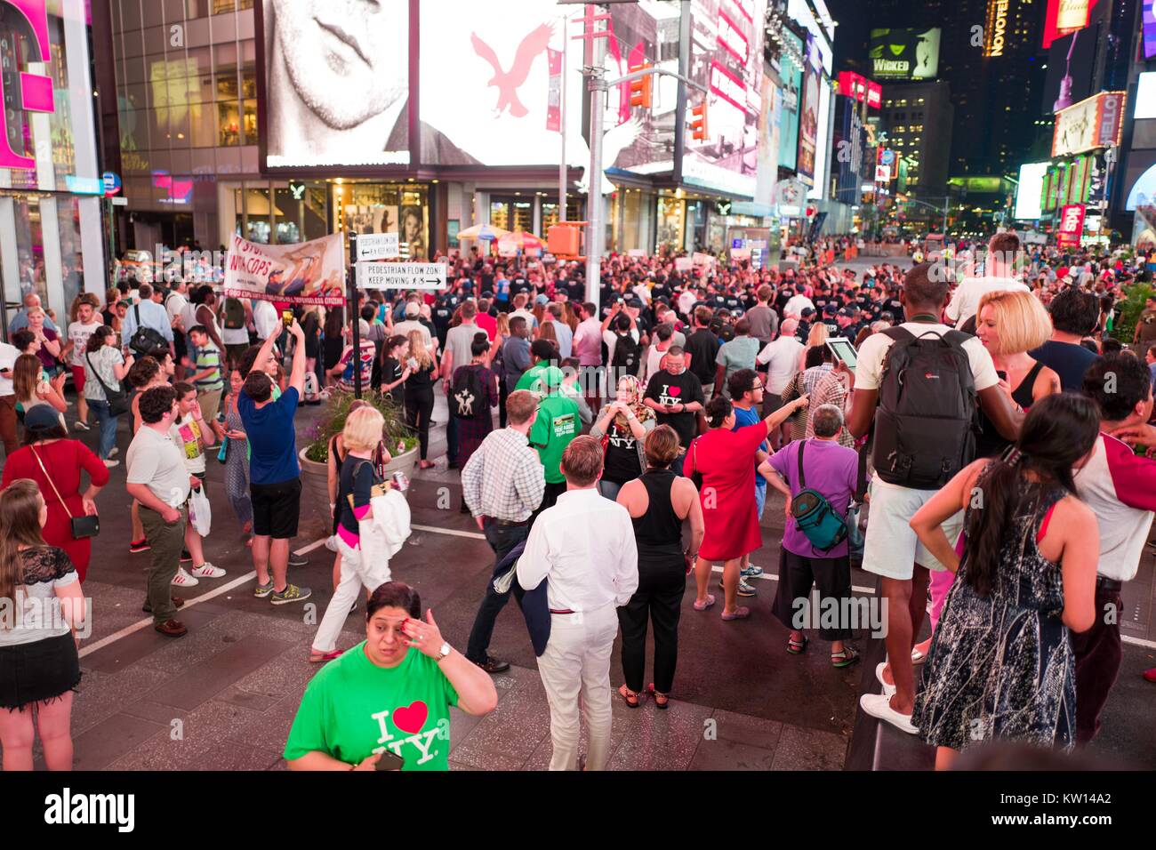 During a Black Lives Matter protest in New York City's Times Square following the shooting deaths of Alton Sterling and Philando Castile, activists block traffic and square off against a line of New York Police Department (NYPD) riot police as tourists look on, 2016. Stock Photo