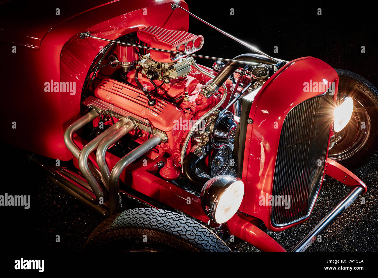 Isolated on black, red Ford hot rod engine showing the detail of the headers, pipes and four barrel carburetor, shot at night using light painting. Stock Photo